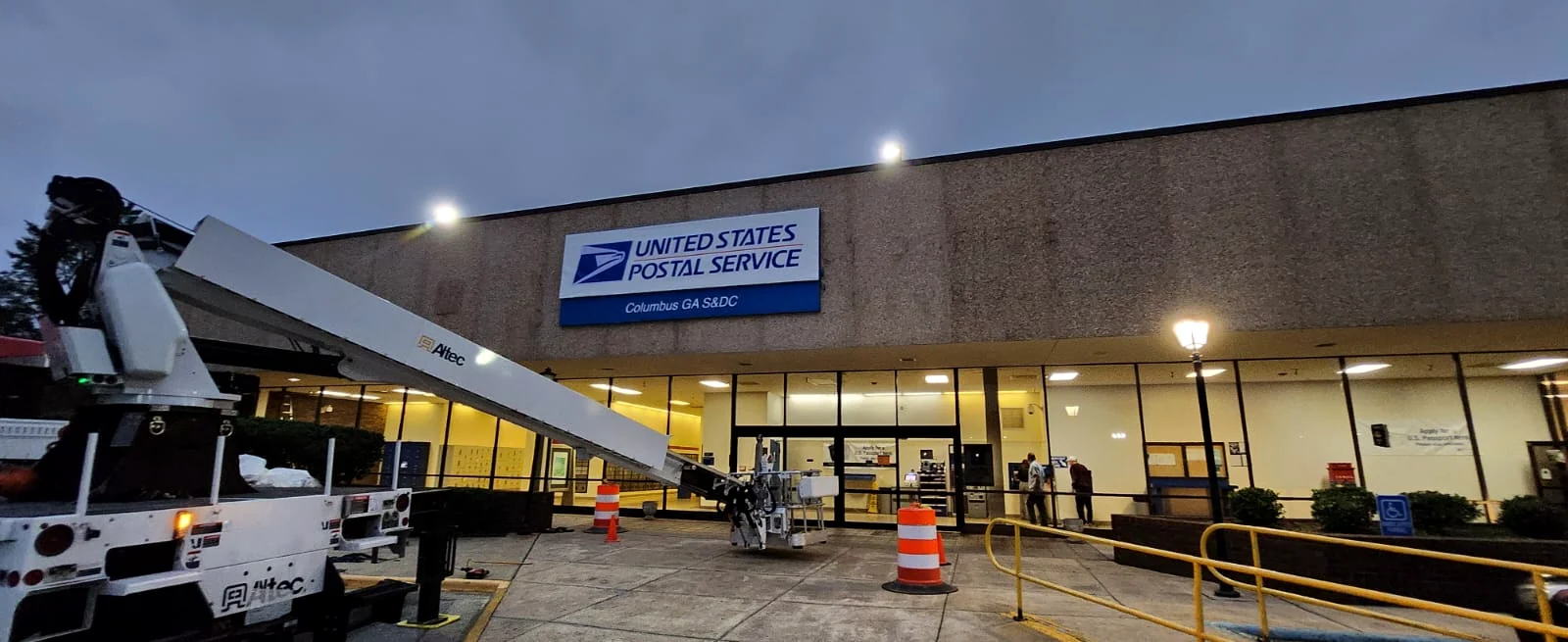 Exterior institutional signage installed above the entrance of a postal service building